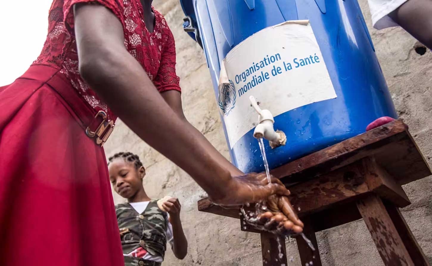 A woman washes her hands at a water tank provided by the World Health Organization. Getty Images