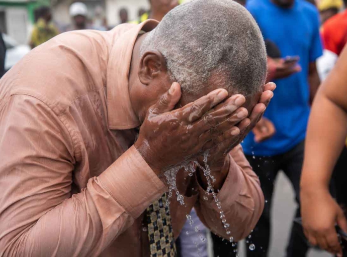 Western Kingston MP Desmond McKenzie washes his face after being pepper sprayed by the polic e in West Kingston on Tuesday.