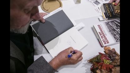 Antero Pietila personally signs a copy of his book, “Not in My Neighborhood: How Bigotry Shaped a Great American City,” for a reader at the 10th Annual Words & Wine Benefit hosted by the Friends of the Catonsville Library in 2015. (Nate Pesce / For The Baltimore Sun Media Group)