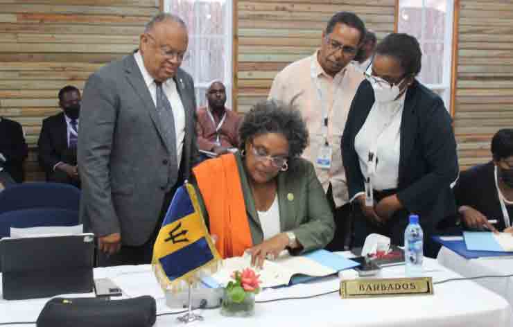 Prime Minister Hon. Mia Mottley of Barbados signs the Protocol as (from left) Barbados Minister of Foreign Affairs Sen, Jerome Walcott; Barbados Ambassador to CARICOM Mr David Comissiong; and CARICOM General Counsel Dr Corlita Babb-Schaefer, look on