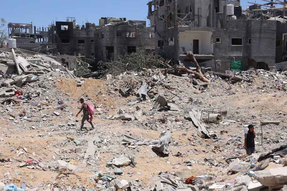 Palestinians walk next to destroyed buildings in the Jabalya refugee camp in northern Gaza on Saturday. (Omar Al-Qattaa/AFP/Getty Images)