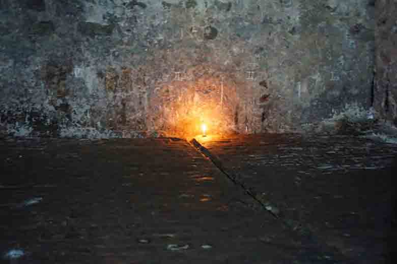 A candle lit in memoriam to the enslaved peoples who once were held captive in this dungeon.