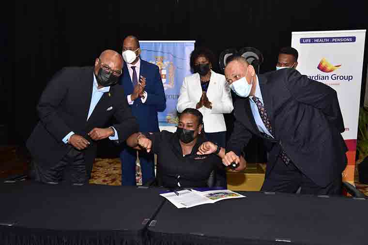 Tourism Workers Pension Scheme Signing: Tourism worker Darnel Mason of VIP Attractions (seated) gets congratulatory elbow bumps from Minister of Tourism, Hon. Edmund Bartlett (left) and Guardian Life President Eric Hosin. Ms. Mason was first to sign on to the historic Tourism Workers Pension Scheme following its official launch at the Montego Bay Convention Centre on Wednesday (January 12). Witnessing the signing were (from left to right) Chairman of the TWPS Board of Trustees, Ryan Parkes; Permanent Secretary in the Ministry of Tourism, Jennifer Griffith and EVP & Chief Investment Officer at Sagicor Group Jamaica, Sean Newman.