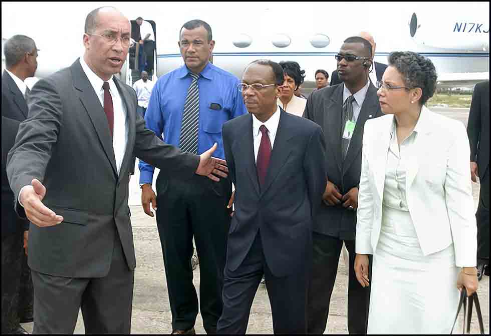 Jean-Bertrand Aristide, center, and his wife Mildred Trouillot, are welcomed at the Kingston, Jamaica, airport by then foreign trade minister, Delano Franklin on March 15, 2004. 