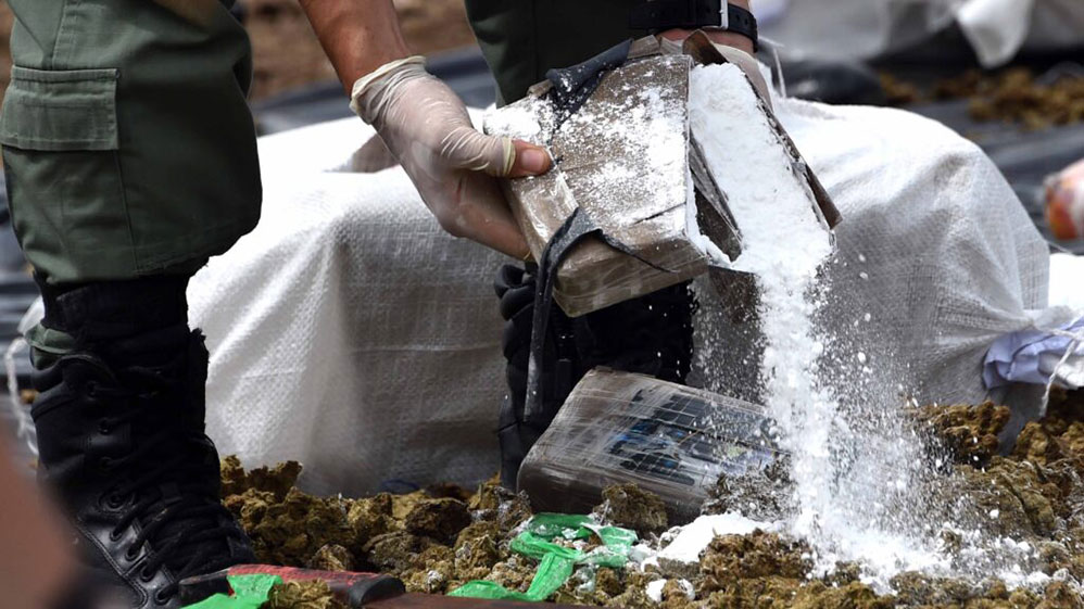 Police personnel inspect parcels of cocaine in an undisclosed area of Jamaica. (Photo: jcf.gov.jm)