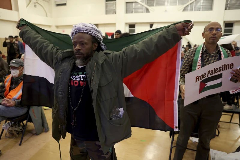 FILE - Jabari Shaw holds a Palestinian flag during an Oakland Unified School District board meeting at La Escuelita Elementary School in Oakland, Calif., on Wednesday, Nov. 8, 2023. (Jane Tyska/Bay Area News Group via AP)