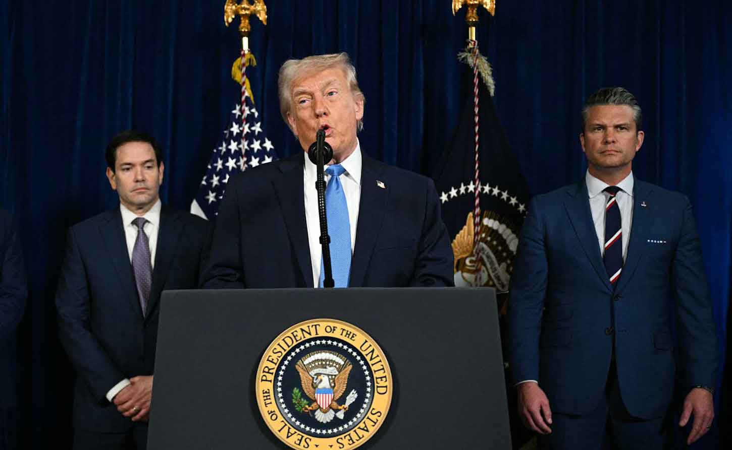 Secretary of State Marco Rubio and Secretary of War Pete Hegseth listen as President Donald Trump addresses the media during a news conference held on 3 January 2026, in Palm Beach, Florida. (Photo by Joe Raedle/Getty Images) 